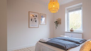 A bedroom with a bed, a window with a view, and two framed pictures on the wall. - Apartment Sleeps 2 With Free Parking (Aalborg)