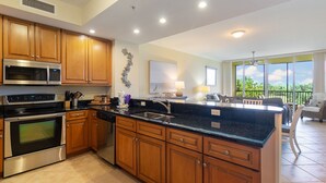 A modern kitchen with wooden cabinets, stainless steel appliances, and a black granite countertop.