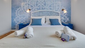A neatly made bed with white and blue bedding, a decorative wall mural, and two bedside tables with lamps. - Family Villa  Pag  2 min from the beach hot tub  - free parking (Pag)