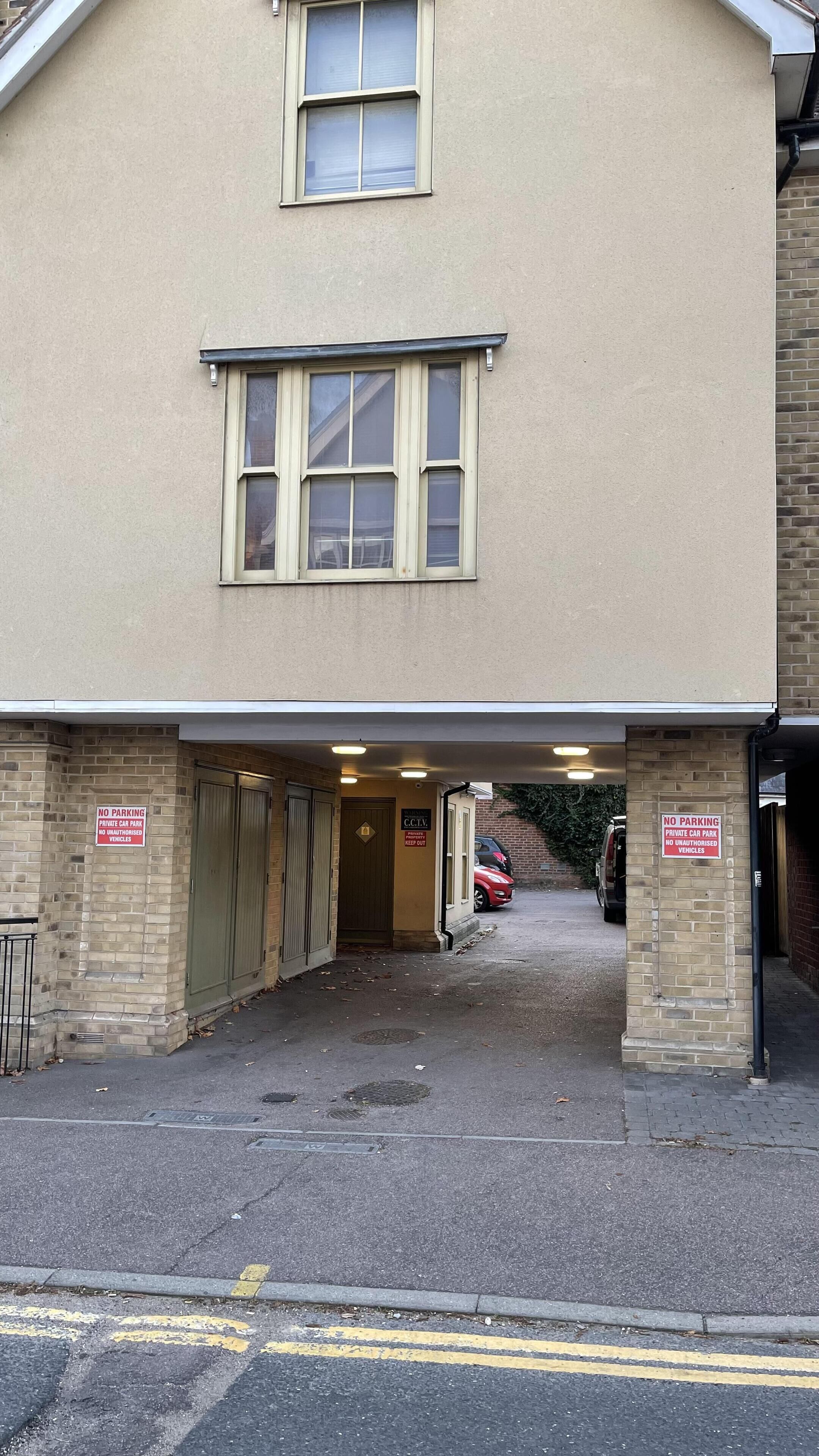 Un edificio con acceso cubierto y dos señales de 'No Estacionar'.