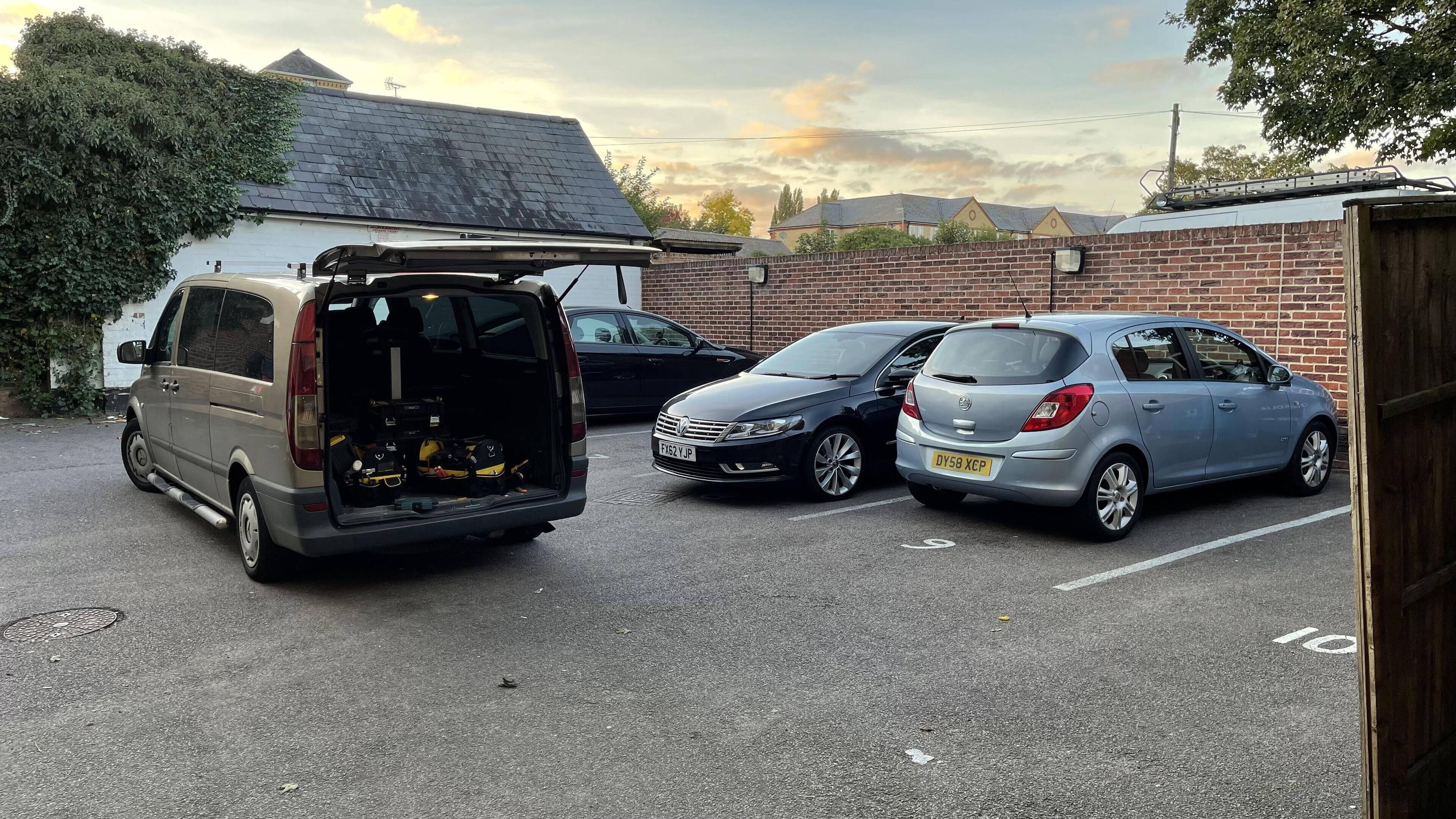 Een parkeerplaats met een bestelwagen en twee auto's.