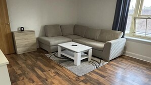 Uma sala de estar moderna com um sofá modular cinza, uma mesa de centro branca e piso de madeira.