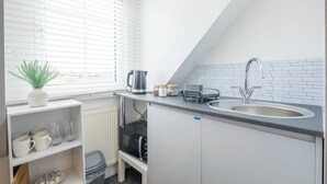 A compact kitchen with a sink, kettle, and storage shelves.