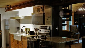 A kitchen with wooden cabinets, a stainless steel refrigerator, a built-in oven, a sink, and a bar stool. - Enjoy A memorable experience in our unique Cabin on Wisconsin River (Mauston)