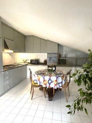 A kitchen with a dining table set for four, surrounded by grey cabinets and a tiled floor. - Fashionable by the canals (Milano)