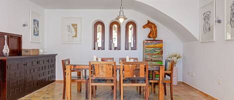 Un comedor con una mesa y sillas de madera, un mueble con varias puertas y un piso de baldosas.