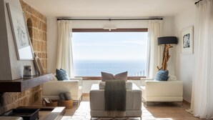 A living room with a view of the sea, a fireplace, and a modern lamp.