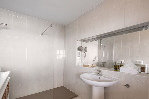 Un baño moderno con lavamanos, espejo y ducha blancos.