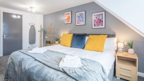 A modern bedroom with a bed, a nightstand, a hanging rack, and abstract wall art.