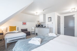 Relax in a spacious room with two single beds, a desk area, and a seating area.