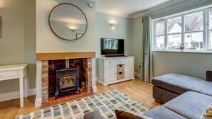 A living room with a fireplace, a television, and a large window. - Walnut Cottage | Evenley Holiday Let | 2 Beds & Sleeps 4 (EVENLEY, NEAR BICESTER)
