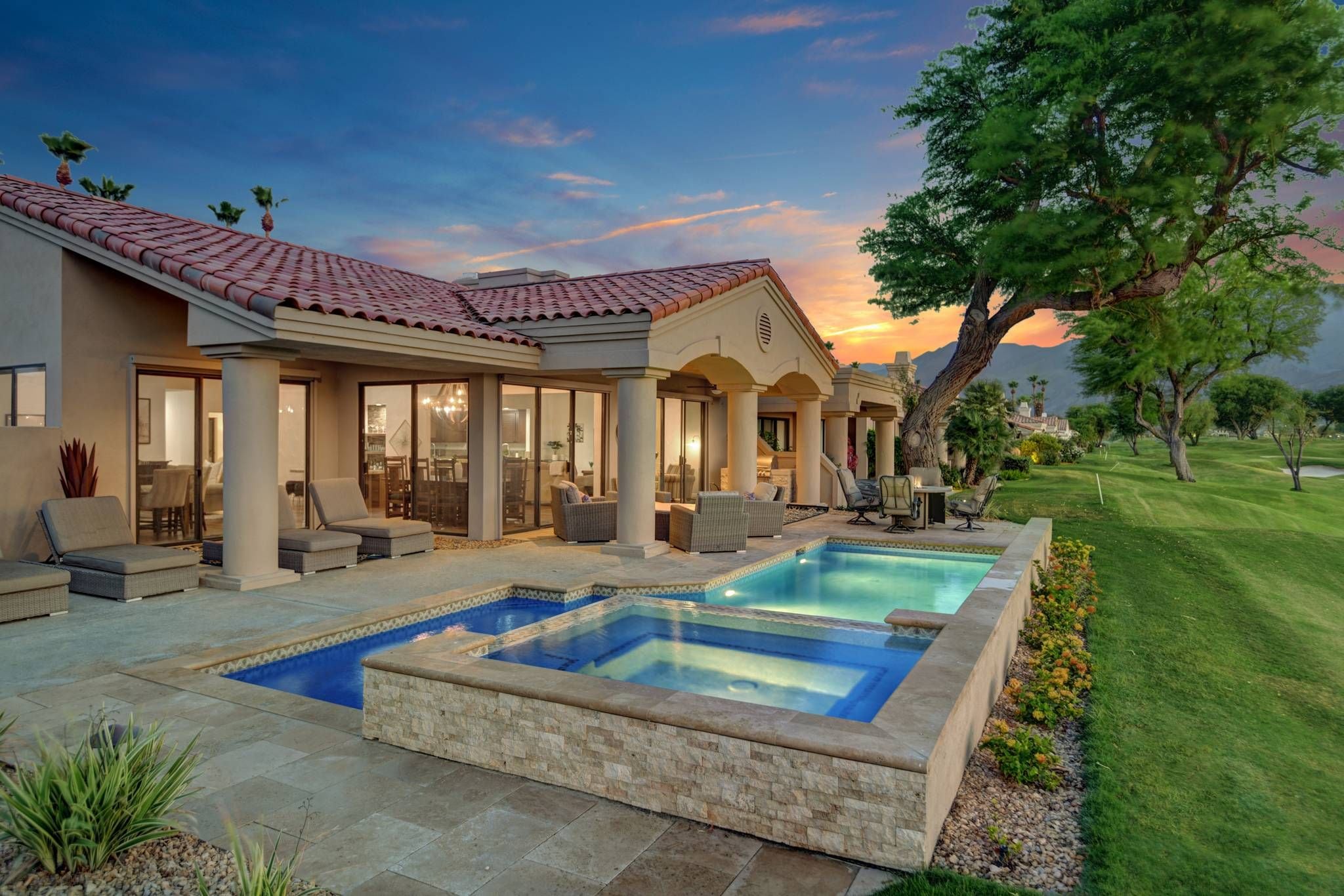 A residential property with a swimming pool, outdoor seating, and a view of the landscape.