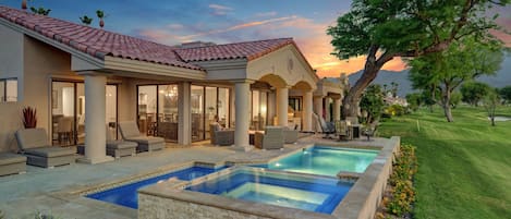 A residential property with a swimming pool, outdoor seating, and a view of the landscape.