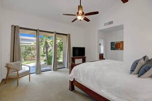 A hotel room with a bed, a chair, a television, and a ceiling fan.