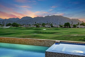 A golf course with a pool in the foreground and mountains in the background.