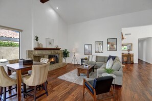 A spacious living room with a fireplace, a dining area, and a sofa.