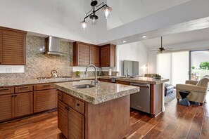 Une cuisine moderne avec des meubles en bois, des plans de travail en granit et un îlot central.