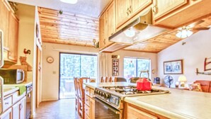 Una cocina con armarios de madera, una estufa y una isla grande. Hay una puerta corrediza de vidrio que da a un balcón.