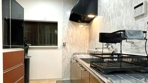 A modern kitchen with wooden cabinets, a stainless steel countertop, and a black range hood. - 【大阪No.1ロケーション】JR大阪駅、人気の梅田エリアから徒歩圏内。大阪観光地、USJ、難波、京都へ好アクセス！ (大阪市北区中津)
