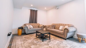 A living room with a sectional sofa, a coffee table, and a small ottoman.