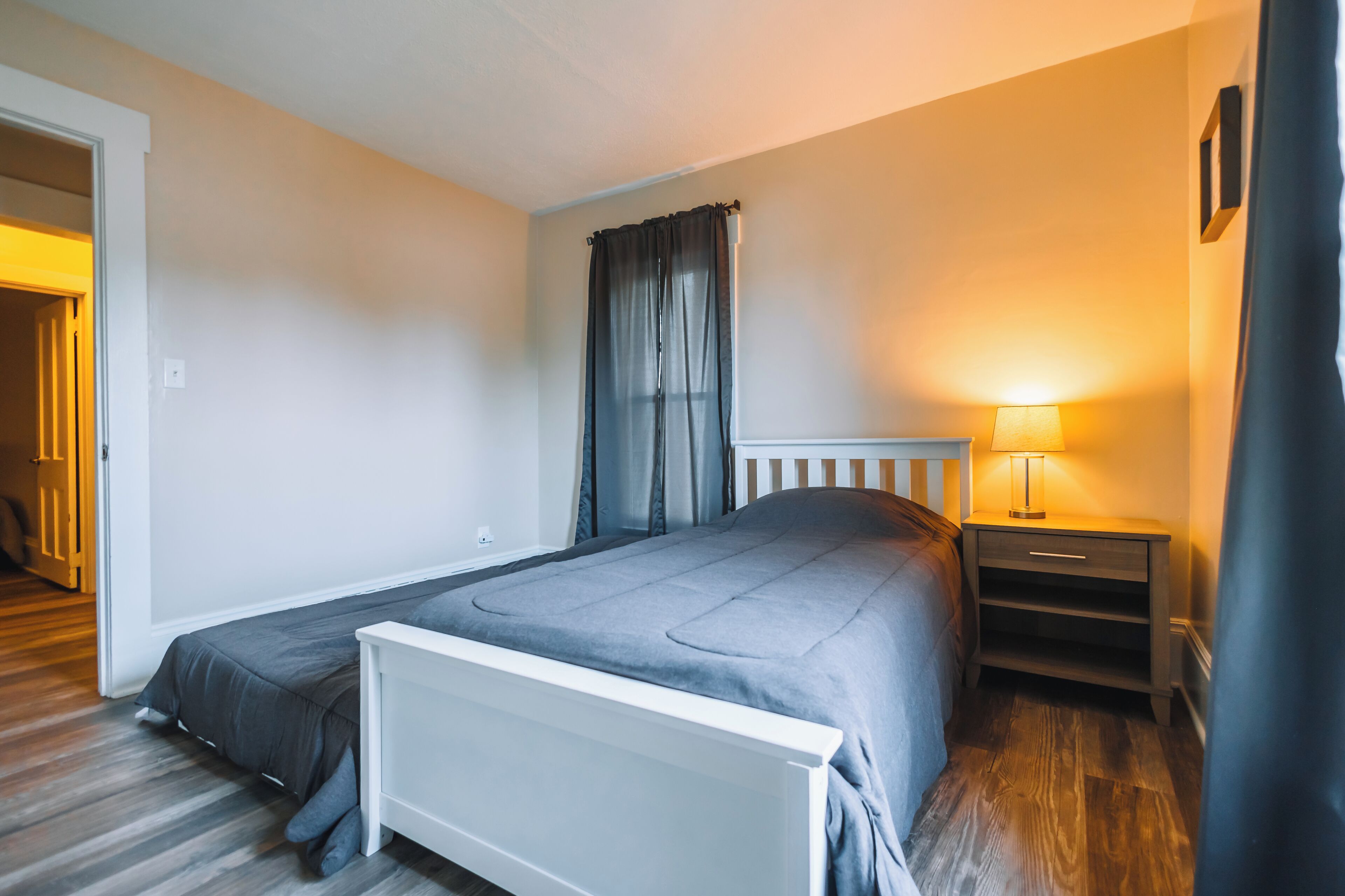 Un dormitorio con cama, mesita de noche y lámpara.