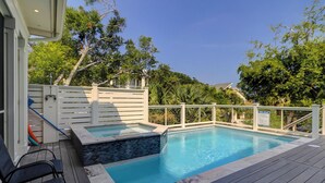 A swimming pool with a wooden deck, a white fence, and a sign indicating pool rules.