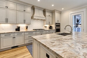 Una cocina moderna con armarios blancos, encimera de mármol y electrodomésticos de acero inoxidable.