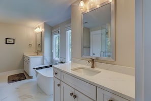 Une salle de bain moderne avec un grand meuble-lavabo, une baignoire et un grand miroir.