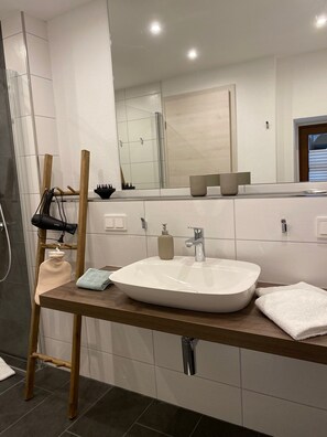 A modern bathroom with a large mirror, a white sink, and a wooden vanity. - Schwarzwaldhof Nicklas (Bonndorf)