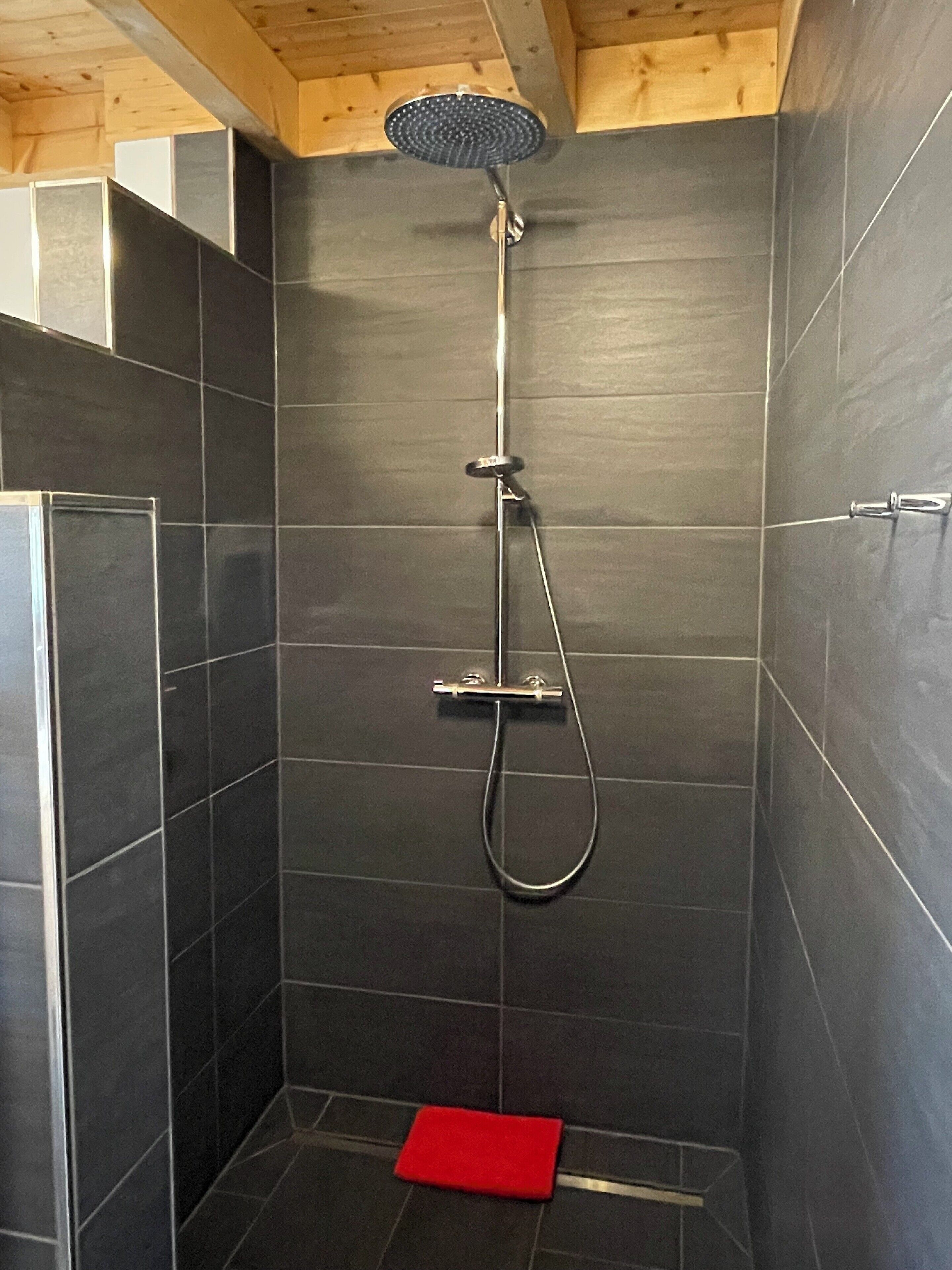 A shower with a handheld showerhead and a handheld showerhead with a circular head.