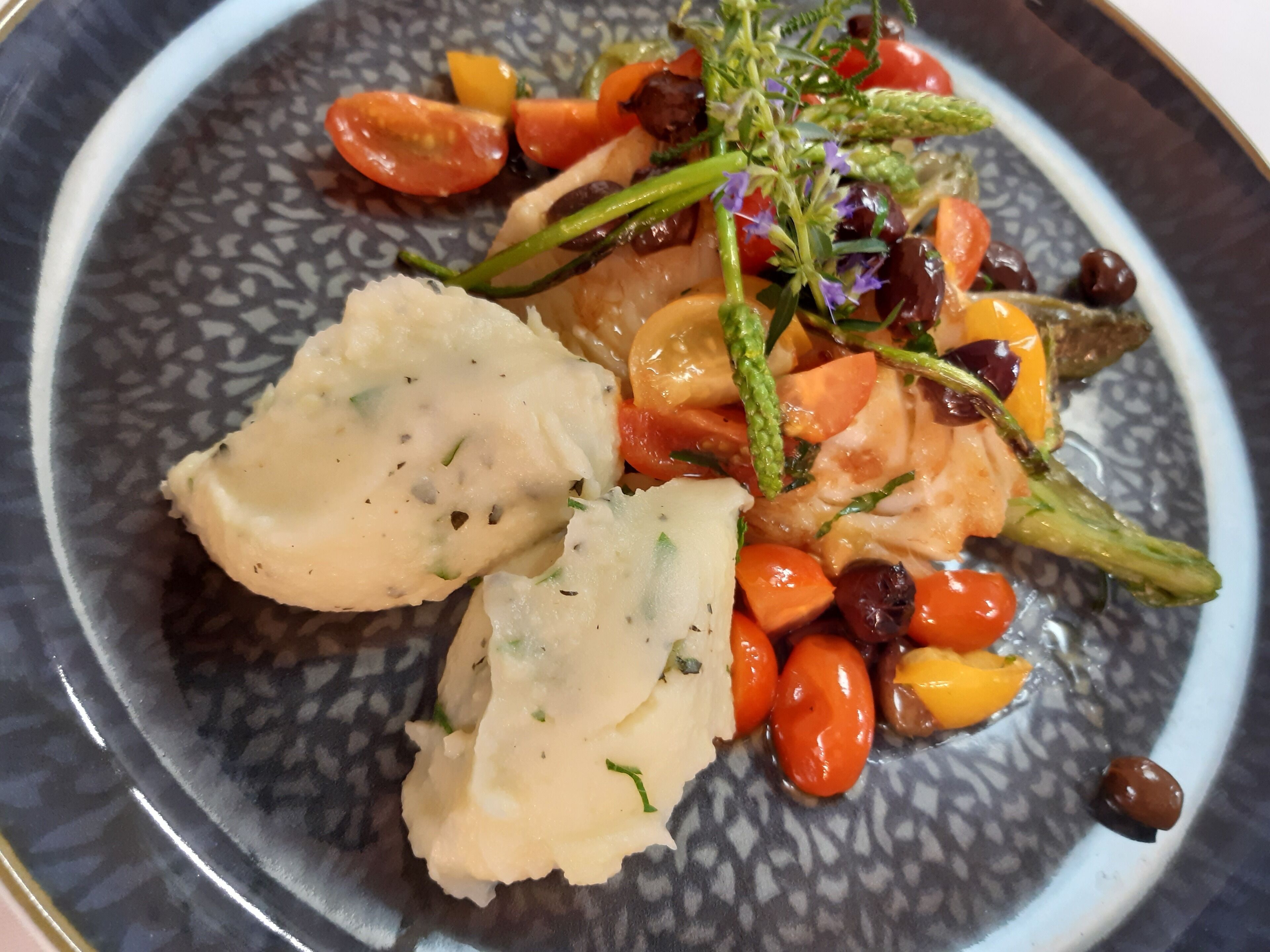 A plate with a piece of salmon, cherry tomatoes, asparagus, and a creamy sauce.