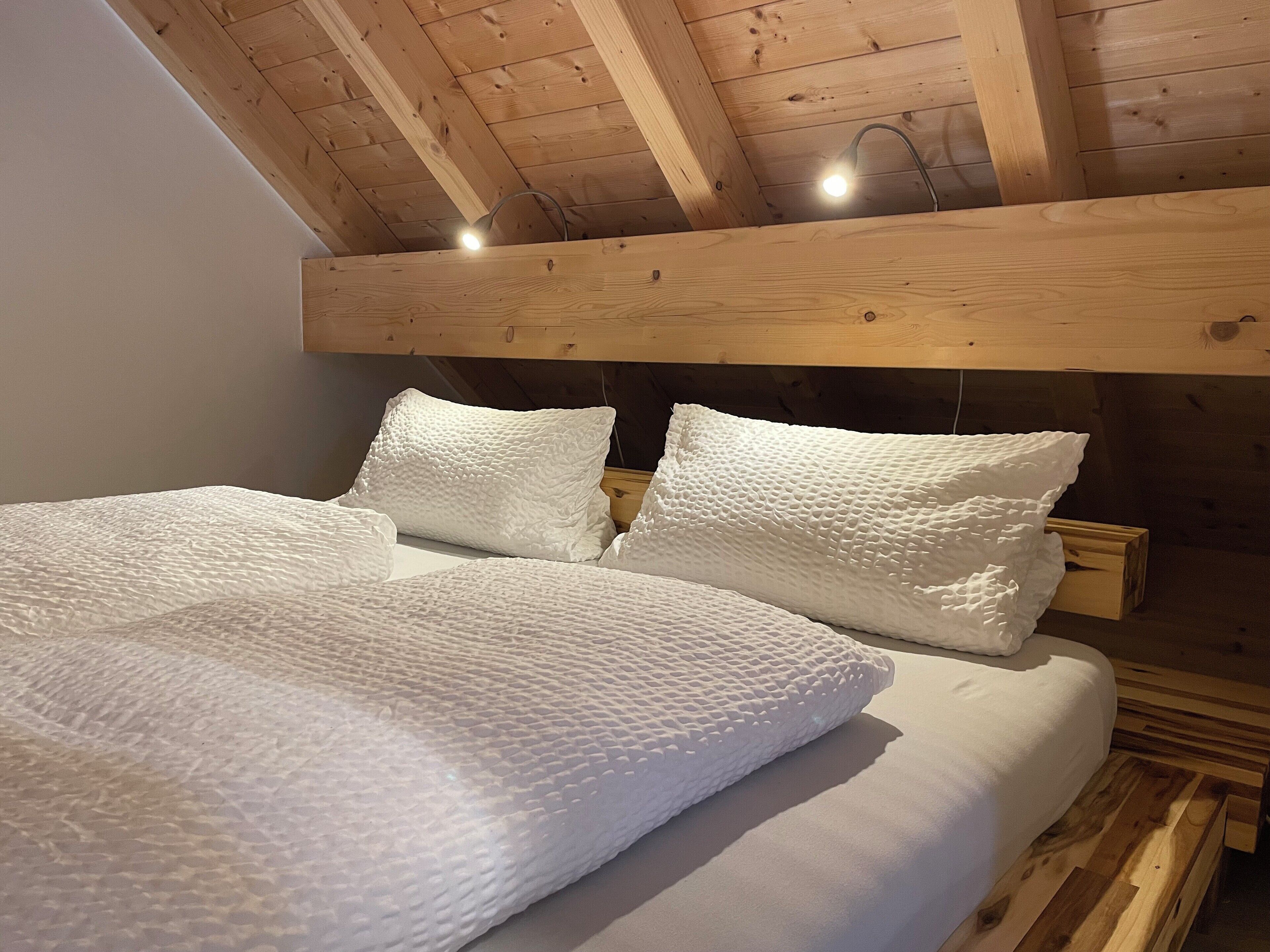 A wooden ceiling with exposed beams and a bed with white textured bedding.