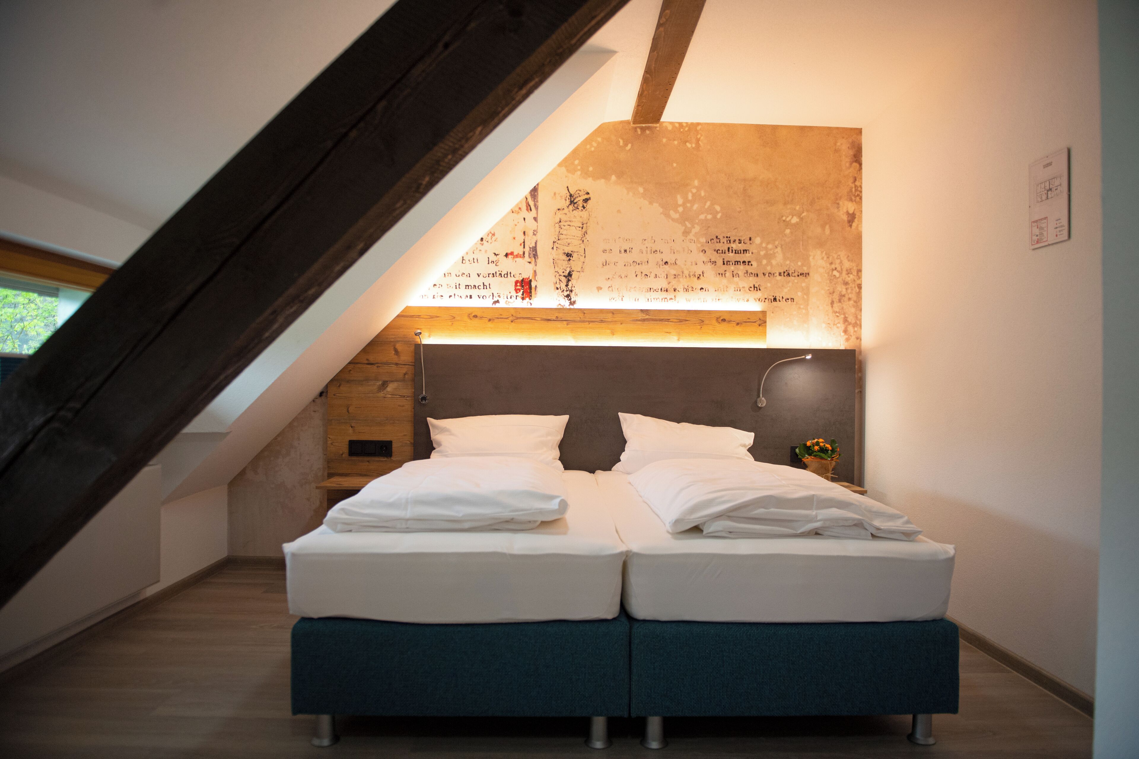 A modern bedroom with a loft-style ceiling, a bed with white linens, and a wooden headboard.