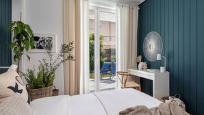 A bedroom with a bed, a desk, a chair, and a view of the outside. - The Southern Mansion (Vari-Voula-Vouliagmeni)