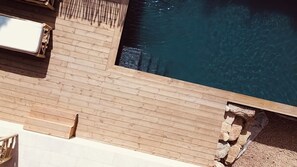 A wooden deck with a pool, a lounge chair, and a small table. - New rental with swimming pool  in corsica (Zonza)