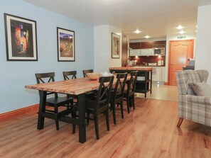 A dining area with a wooden table and chairs, a kitchen in the background, and framed pictures on the wall. - 5 St. Mary's Church (Moffat)