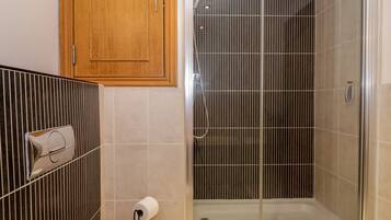 Un baño con ducha, inodoro y un armario de madera.