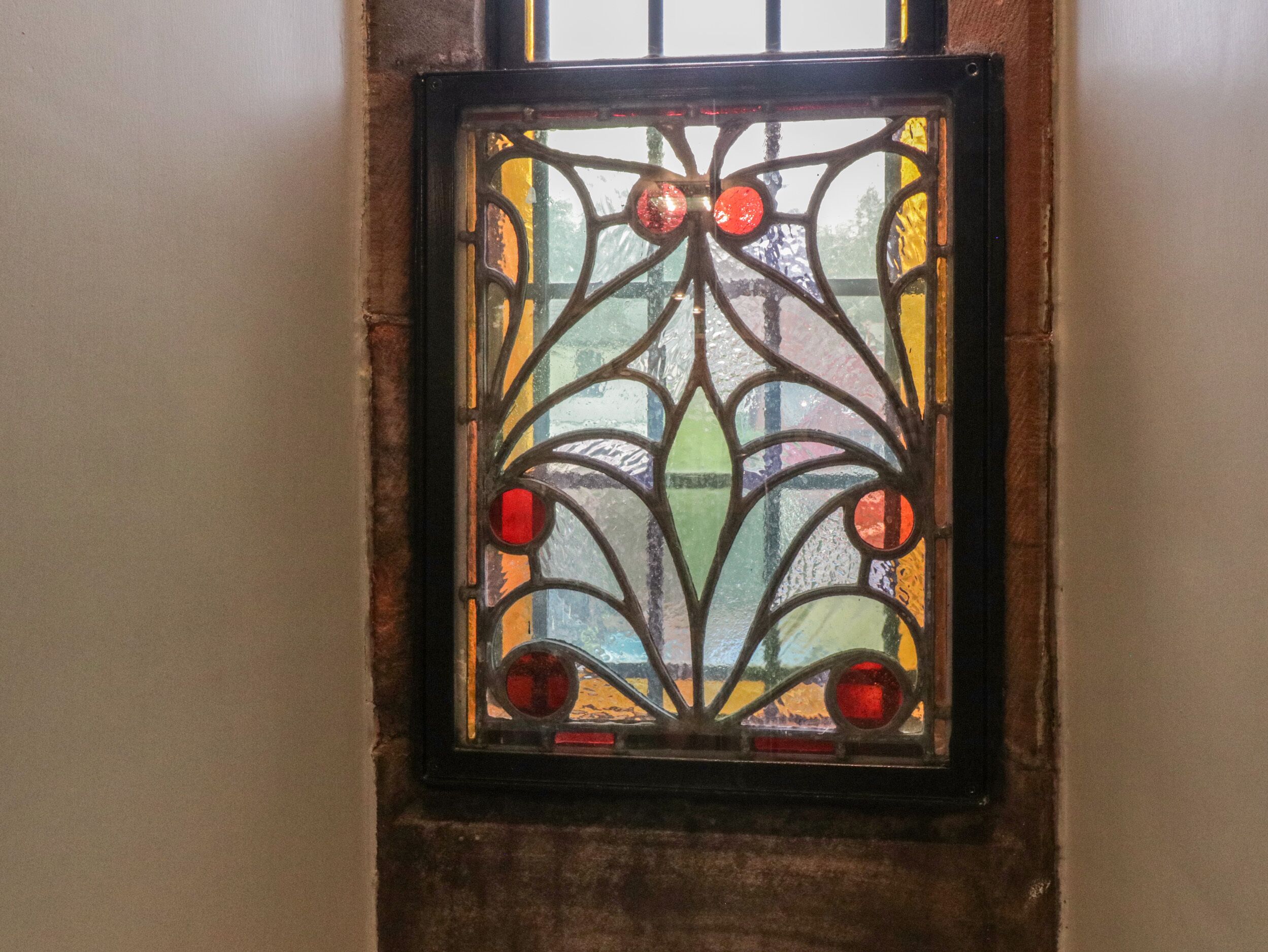 A stained glass window with a geometric design and red accents.