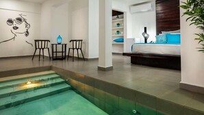 A modern hotel room with a glass-bottomed pool, a bed with blue bedding, and a minimalist decor. - The Diamond Suites at Ahnvee (Sosúa)