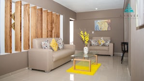 A modern living room with two sofas, a glass coffee table, and a yellow rug. - The Diamond Suites at Ahnvee (Sosúa)