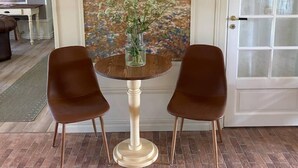 Un comedor con una mesa y dos sillas, un cuadro en la pared y una puerta con paneles de vidrio esmerilado.