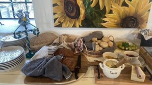 Una encimera de cocina con diversos alimentos, un cuadro de girasoles y una ventana con vistas al verdor.