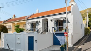 A white building with a red-tiled roof, a blue garage door, and a staircase leading to the entrance. - Torbay 31 (Cape Town)