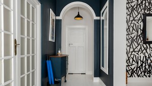 A hallway with a white door, a blue cabinet, and a patterned wall. - Torbay 31 (Cape Town)