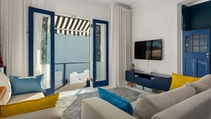A modern living room with a sofa, a TV, and a balcony with a view. - Torbay 31 (Cape Town)