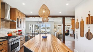 Una cocina moderna con una isla grande, electrodomésticos de acero inoxidable y una lámpara colgante.