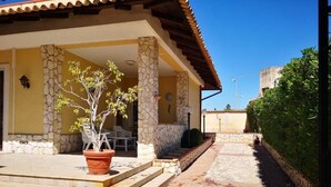 A house with a stone exterior, a tiled patio, and a potted tree. - Villa Lucia Fontane Bianche (Fontane Bianche)