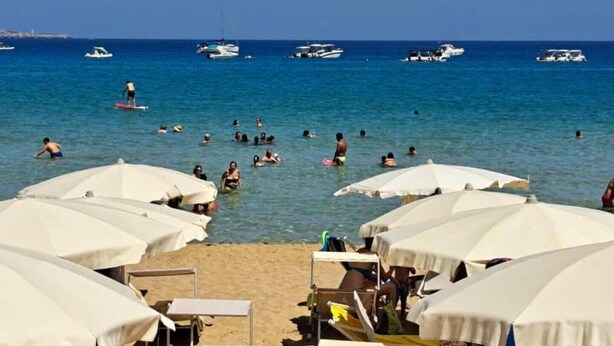 A beach with people swimming and sunbathing under white umbrellas. - Villa Lucia Fontane Bianche (Fontane Bianche)