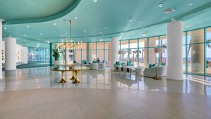 A spacious lobby with a teal ceiling, large windows, and modern seating areas. - Turquoise Place 2402C by Liquid Life (Orange Beach)