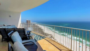 A balcony with a view of the ocean, equipped with lounge chairs and a table. - Turquoise Place 2402C by Liquid Life (Orange Beach)